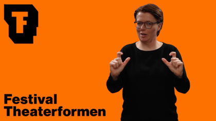 Ein Standbild aus dem Video: Eine Person mit Brille, kurzen braunen Haaren und schwarzem Oberteil gebärdet vor einer orangefarbenen Fläche. Links oben im Bild ist das Theaterformen-Logo zu sehen. Links unten steht: Festival Theaterformen.
