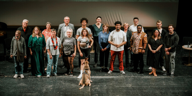 Group photo: All the speakers at the event stand together as a group, a dog sits in front of them and looks at the person standing in the centre.
