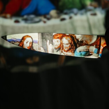 Eine Messerklinge, auf die breite Fläche ist das Gemälde "Das letzte Abendmahl" von Leonardo da Vinci projiziert.