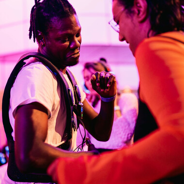 Two people dance. One person wears a black vibrating waistcoat.