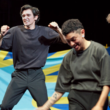 Two people in dynamic poses in front of a blue and yellow cloth.