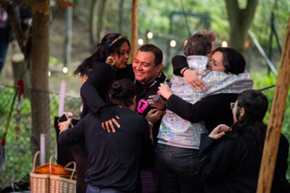 Naine Terena, Denilson Baniwa, Gustavo Caboco Wapichana, Jamille Pinheiro Dias, Anna Mülter und Jacq Azarmi Eskandani umarmen sich alle auf der Bühne im Festivalzentrum Gartenhaus Haeckel. Alle bis auf Anna Mülter tragen dunkle Kleidung, Anna hat einen grau-glitzernden Kapuzenpulli an.