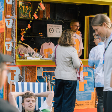 Die Infobox von Festival Theaterformen, beklebt mit Postern. Im Bild sind fünf Personen zu sehen.