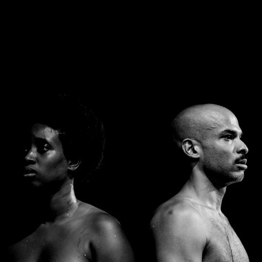 Image description by the editorial staff of Festival Theaterformen. Self-description of the depicted persons follows. / A black and white photo in front of a black background. Two naked performers from the chest up, facing away from each other. They are both sweaty. 