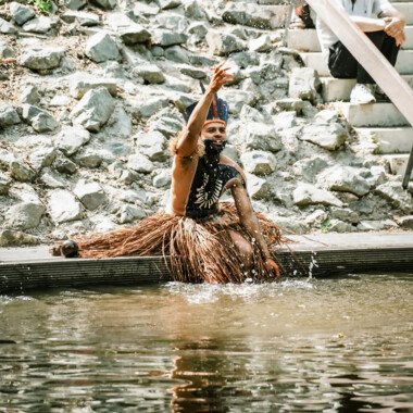 A man in traditional attire splashes water into the air during a performance.