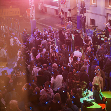 A bird's eye view of a crowd with blue glowing headphones.
