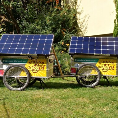 Zwei Fahrradanhänger mit Solarpanels und dem Schriftzug: "Cinema del Sol"